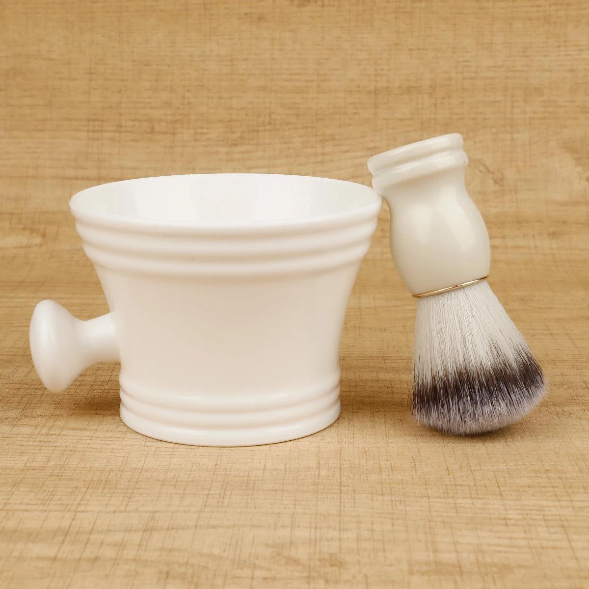 White ceramic shaving mug and brush with black bristles on a beige background