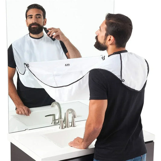 Man using a mirror with a beard-trimming cape in a bathroom setting.