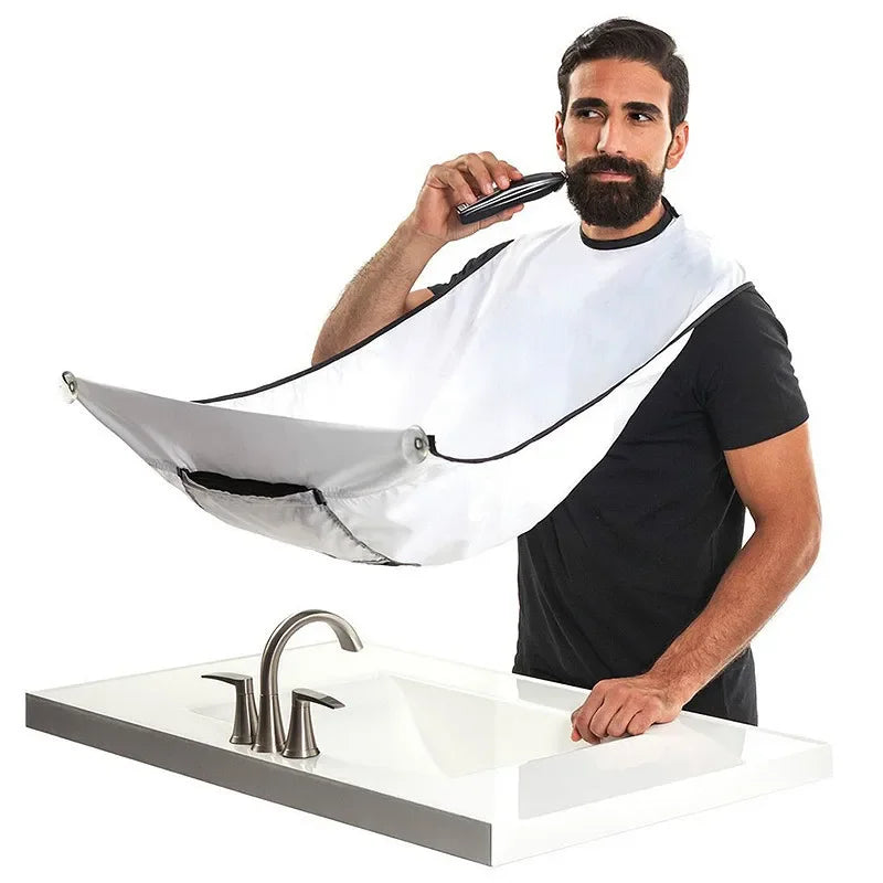 Man using a hair dryer with a white bib over his clothes in a bathroom setting.