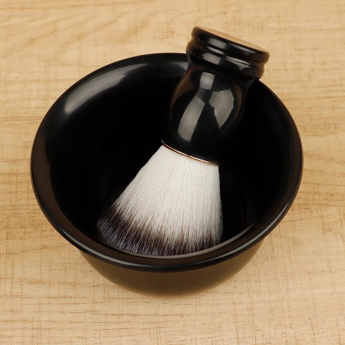 Black bowl with a white brush inside on a wooden surface