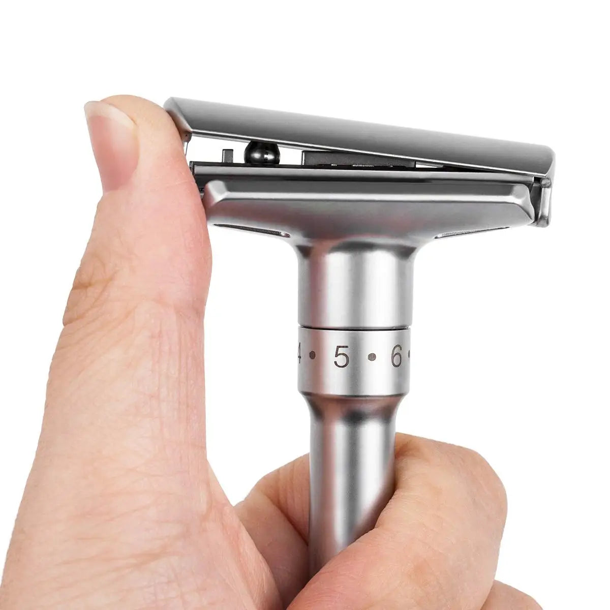 Silver safety razor held by a hand on a white background