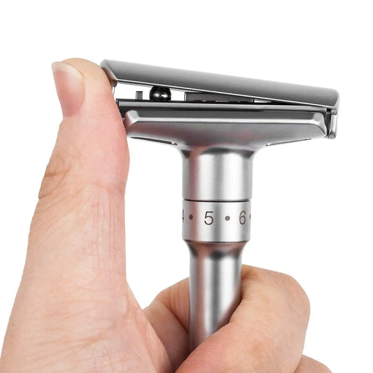 Silver safety razor held by a hand on a white background