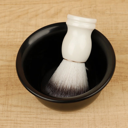 White shaving brush with black bristles in a black bowl on a wooden surface
